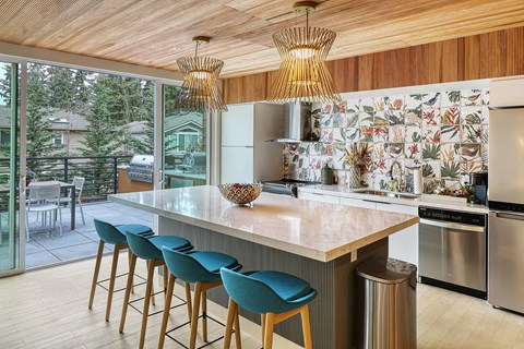 a kitchen with a large island with a marble countertop and blue chairs